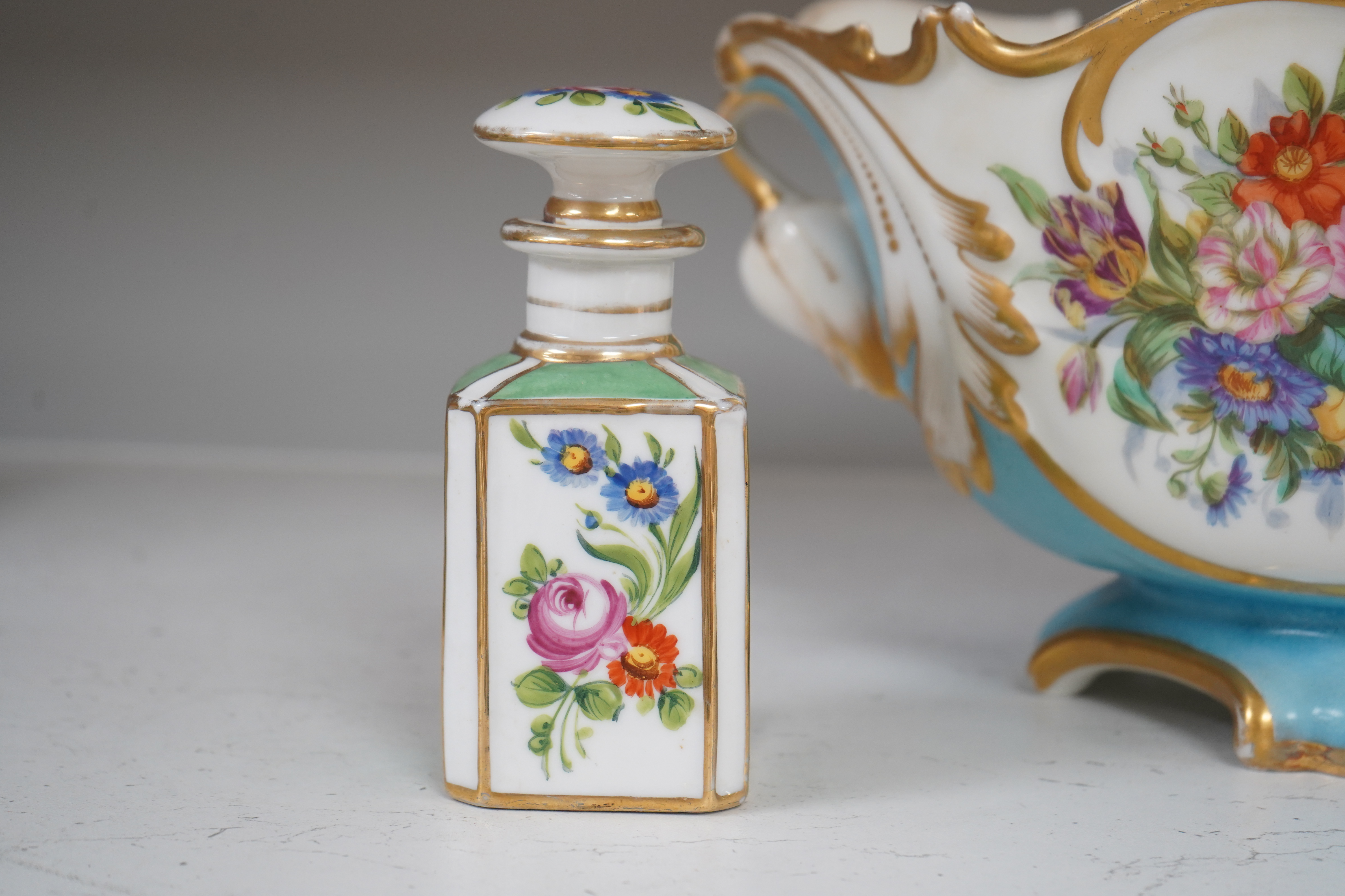 A Sevres style flower painted navette shaped jardiniere and a similar French scent bottle and stopper, late 19th century, largest 38cm wide. Condition - fair to good